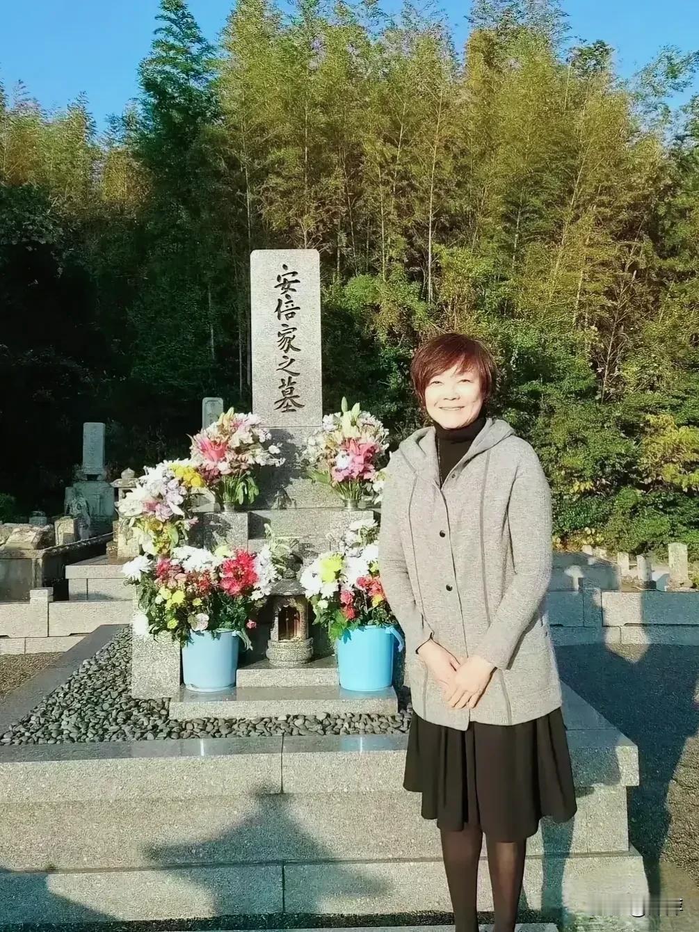 安倍晋三的妻子在他的墓前微笑留影。