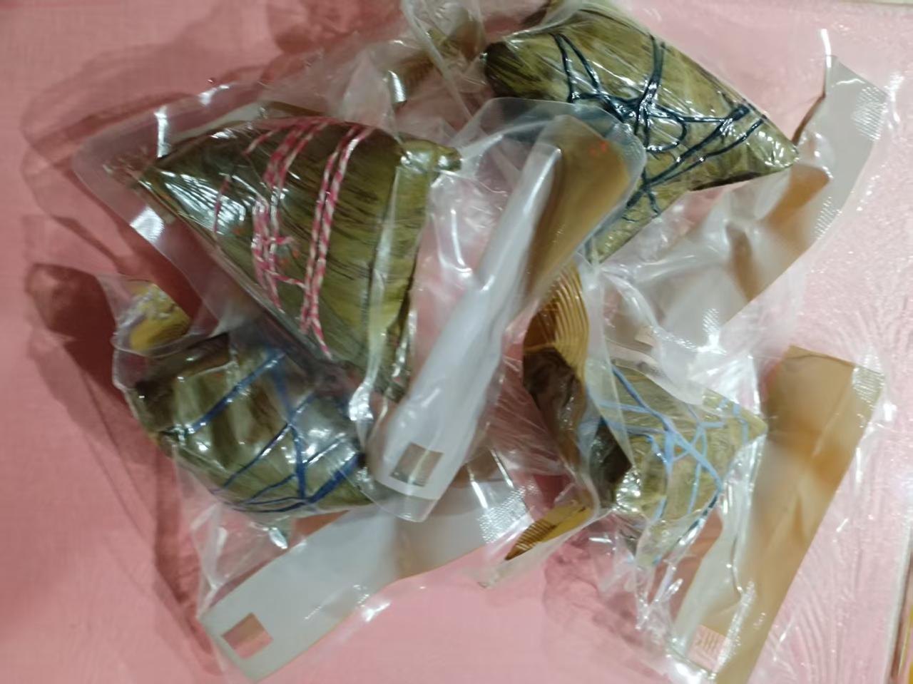 友人送来的粽子品类丰富，各色外观对应不同口味：黑色包装为蛋黄肉粽，红色是经典鲜肉