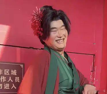 “大衣哥”, 现年56岁, 其现身于万岁山景区进行商演, 他男扮女装，穿上了王婆