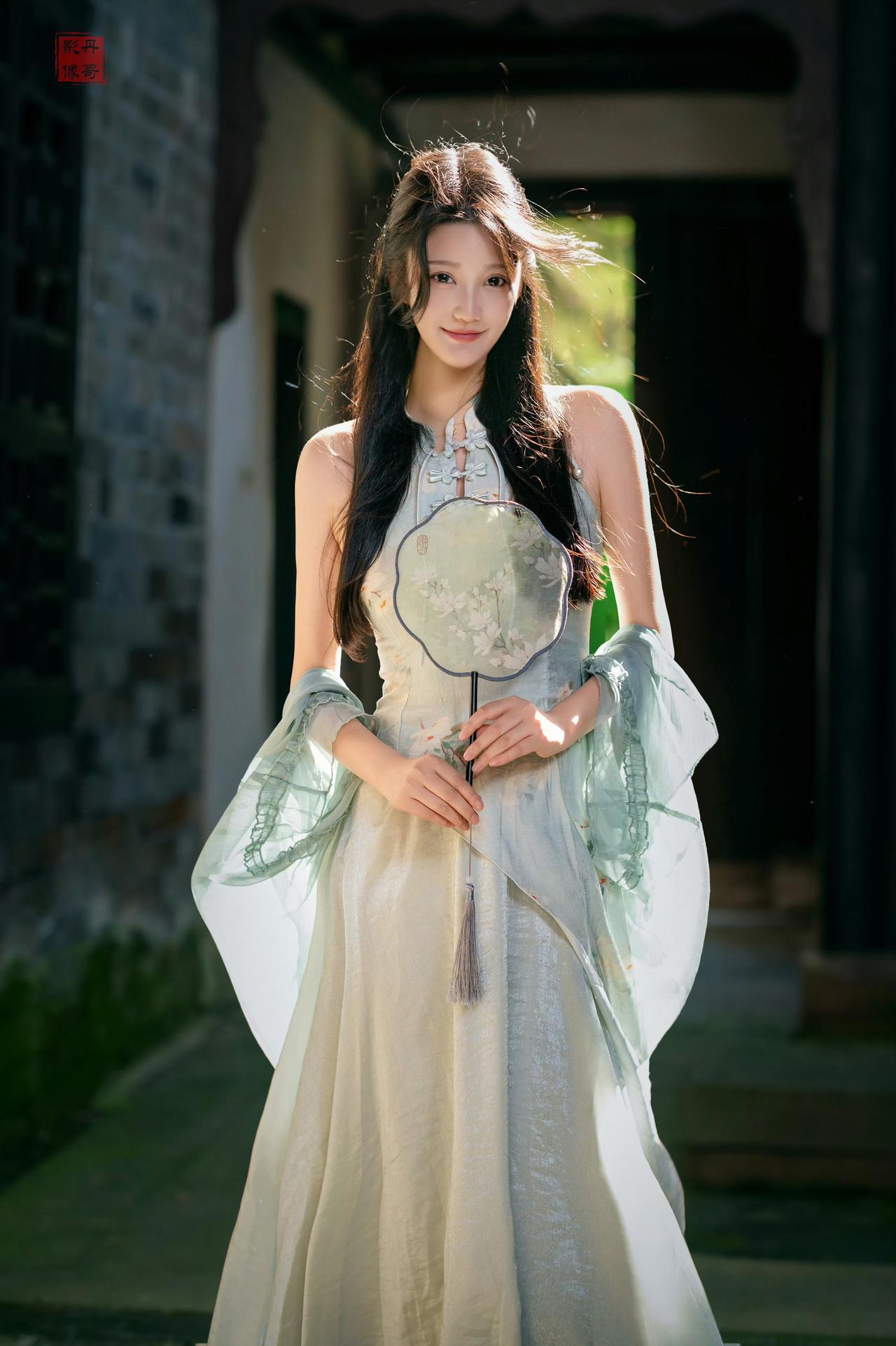 浅绿色刺绣汉服，团扇，在阳光侧洒的砖墙与木门间展现温柔神情。而光影与汉服的搭配，