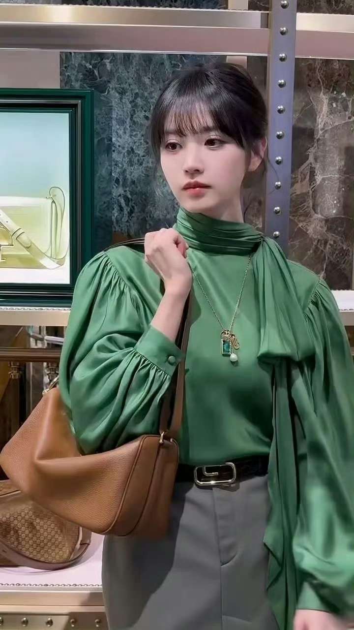 袭墨绿色高领衬衫，缎面材质自带柔光质感，泡泡袖+领口飘带的设计复古又灵动，搭配灰