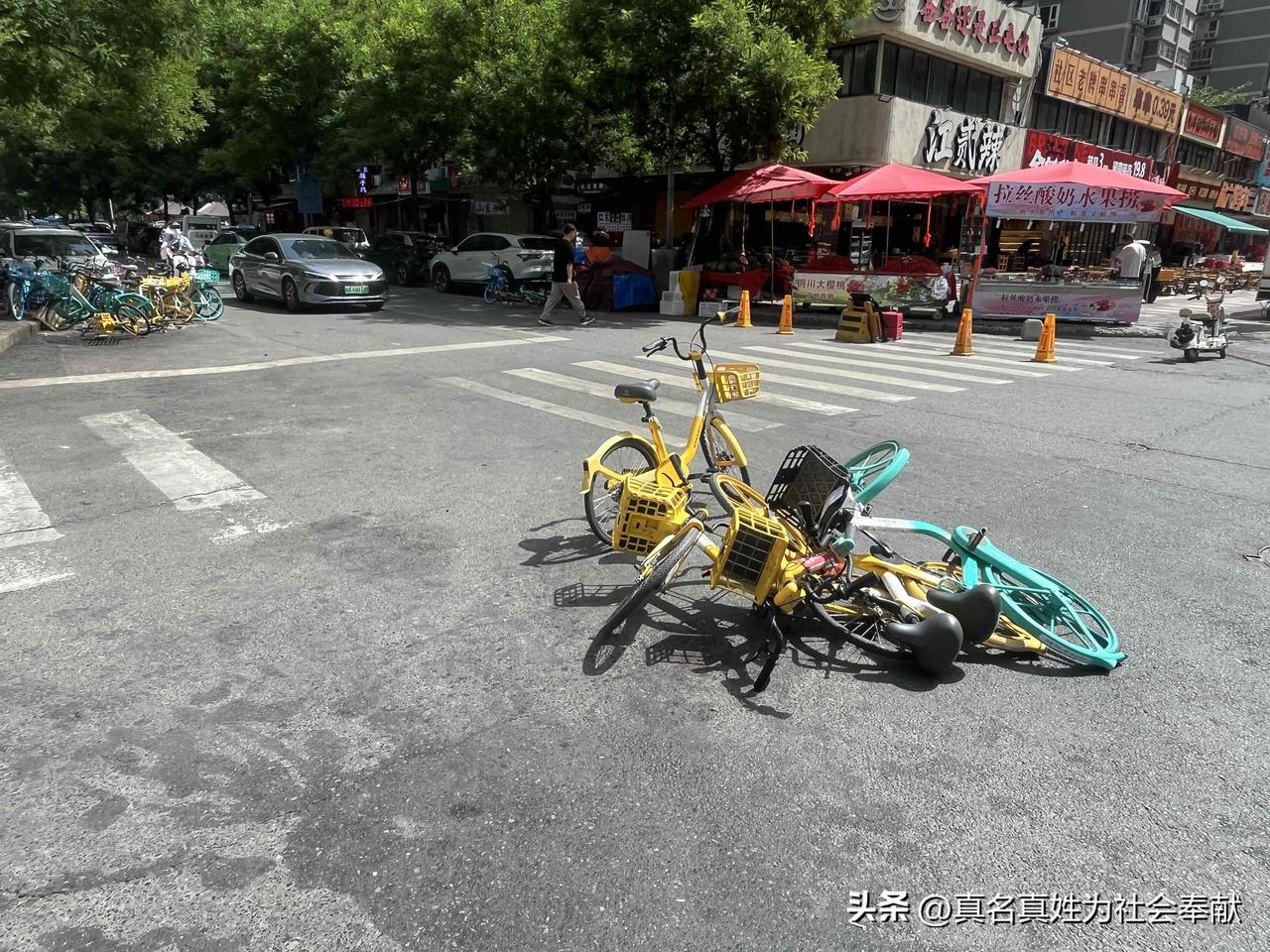 这一堆自行车横七竖八地倒在马路中央，却不见有哪位好心人将它们扶起，如今真是个“各