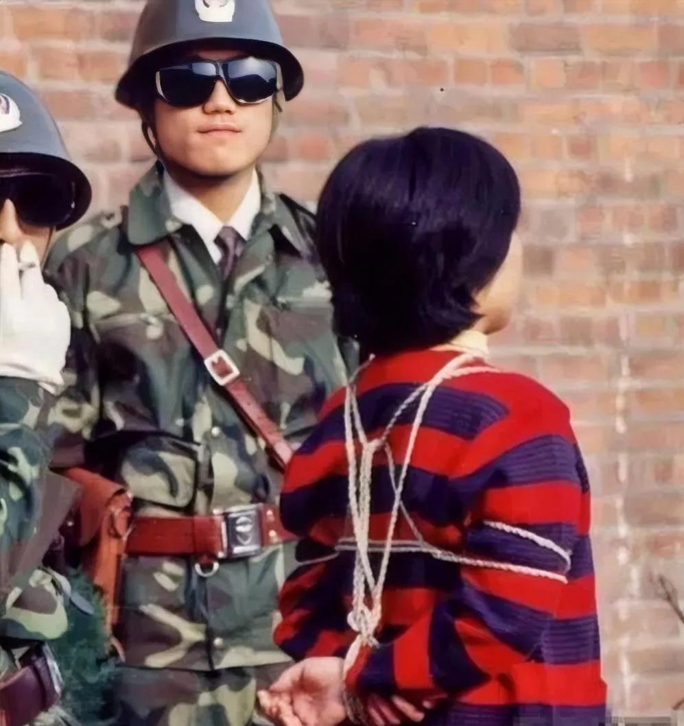 90年代，两名武警，荷枪实弹，准备将犯人押赴刑场，照片中的他们戴着墨镜，仔细看死