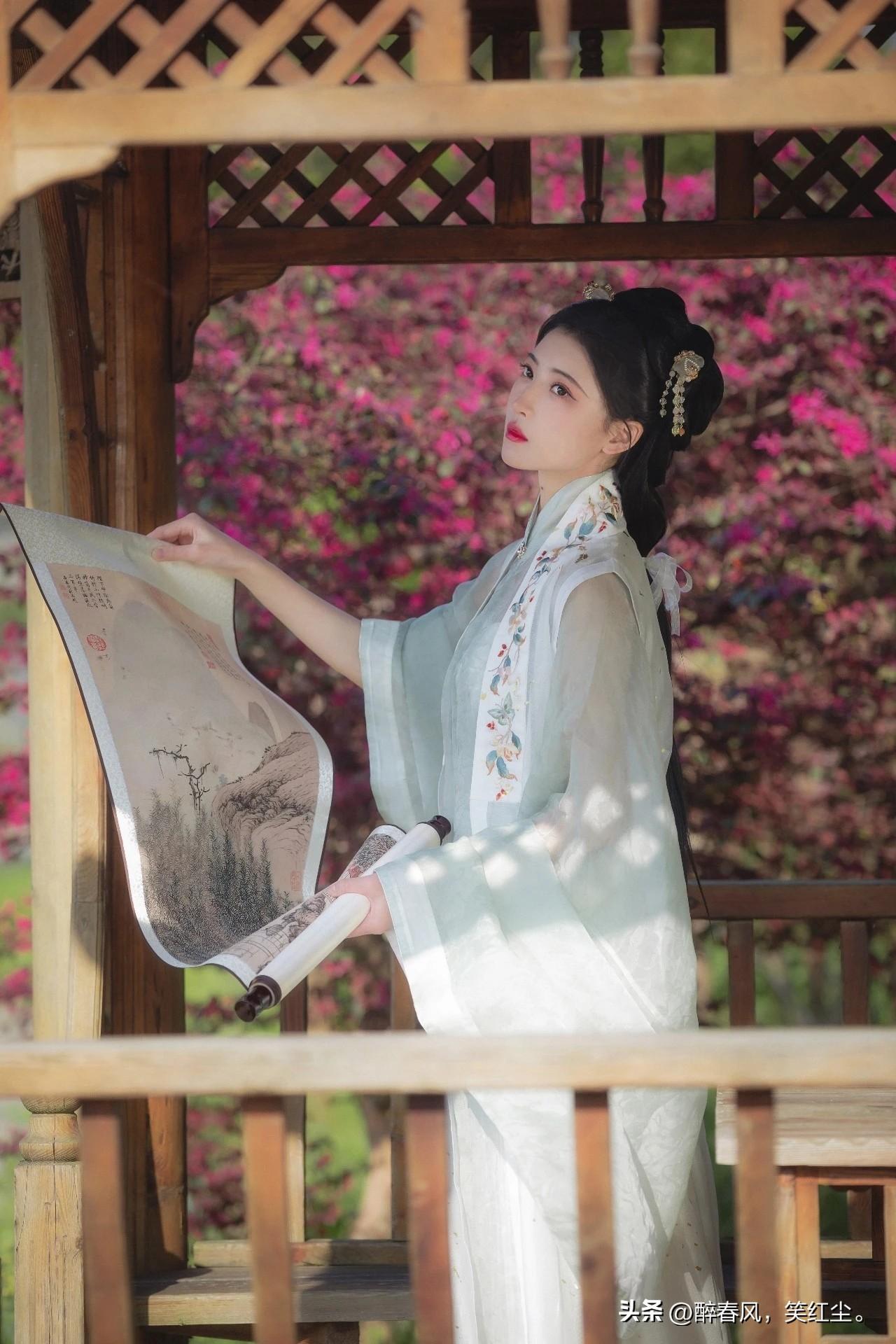 像是从山水画里走出的仙子。
身畔是碧波荡漾的江水，
身后是连绵起伏的青山。
不需
