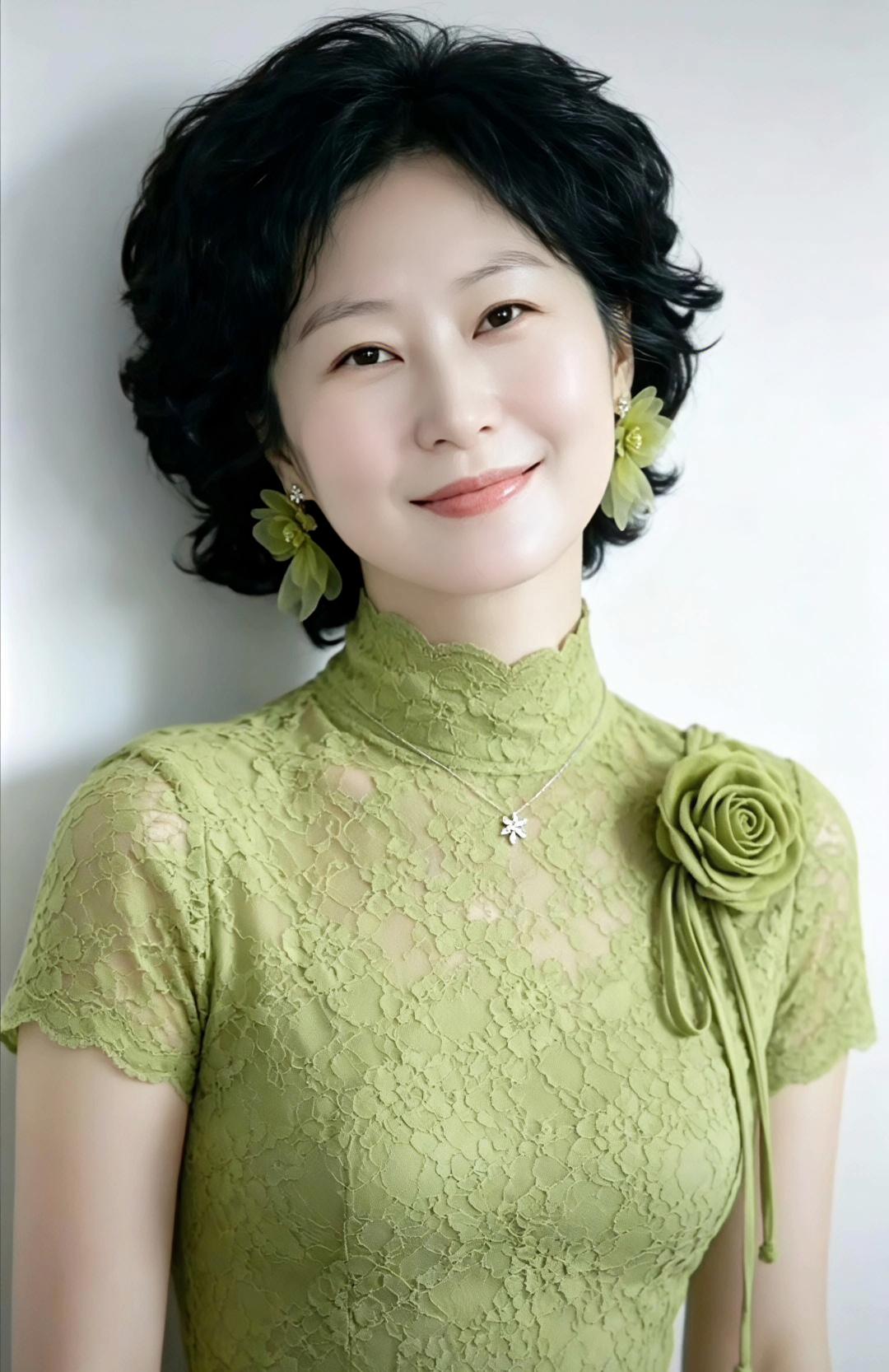 这位女士穿着绿色蕾丝裙，搭配着漂亮的花饰。