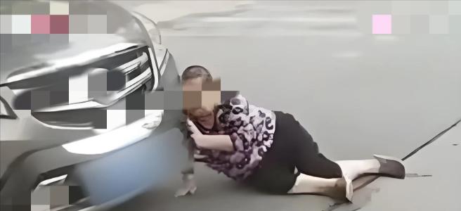 辽宁沈阳，大妈看路边停放了一辆好车，用身体蹭上车灯，然后就躺在车前面，静等着司机