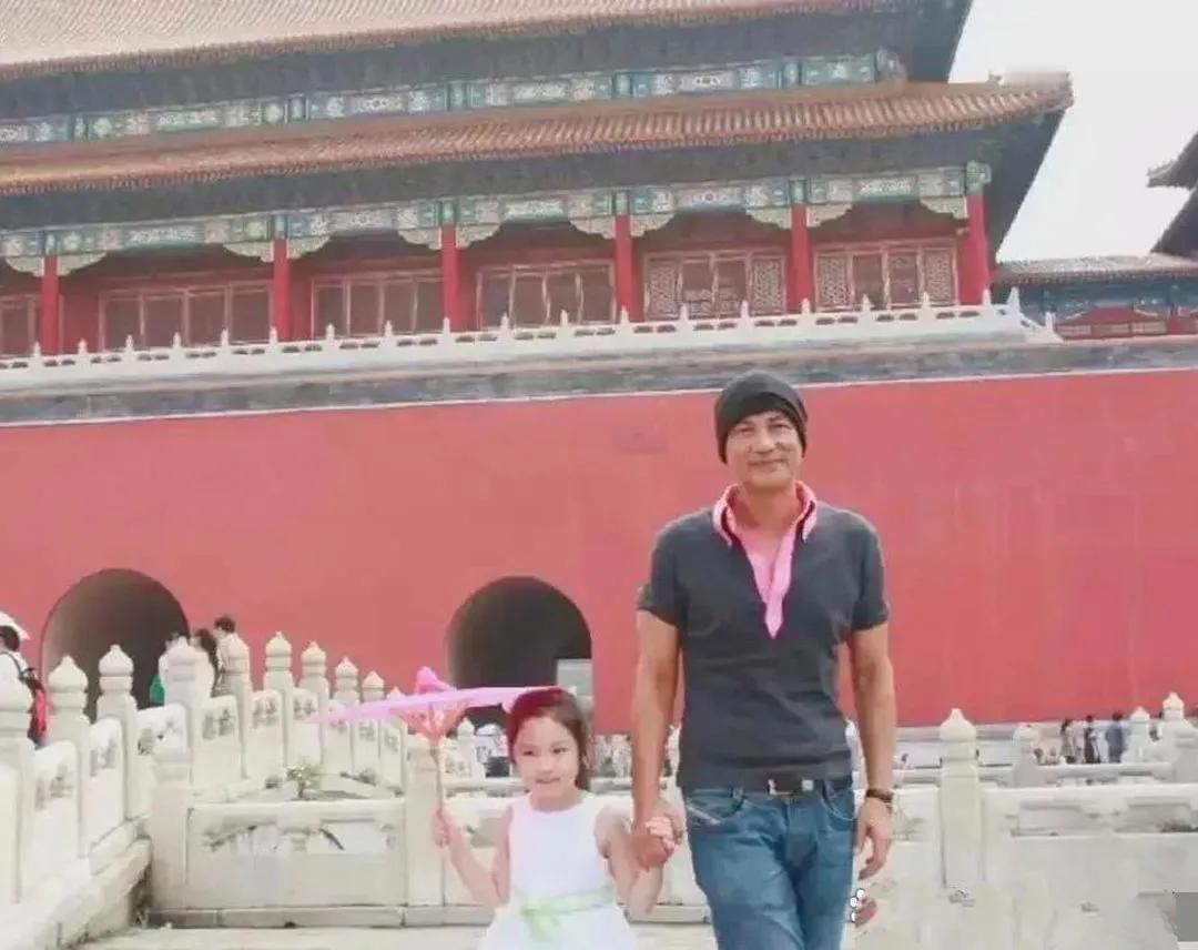 任达华带女儿任晴佳小时候游览故宫看照片，那时候任达华又帅又有型，黝黑的肌肤，黑色