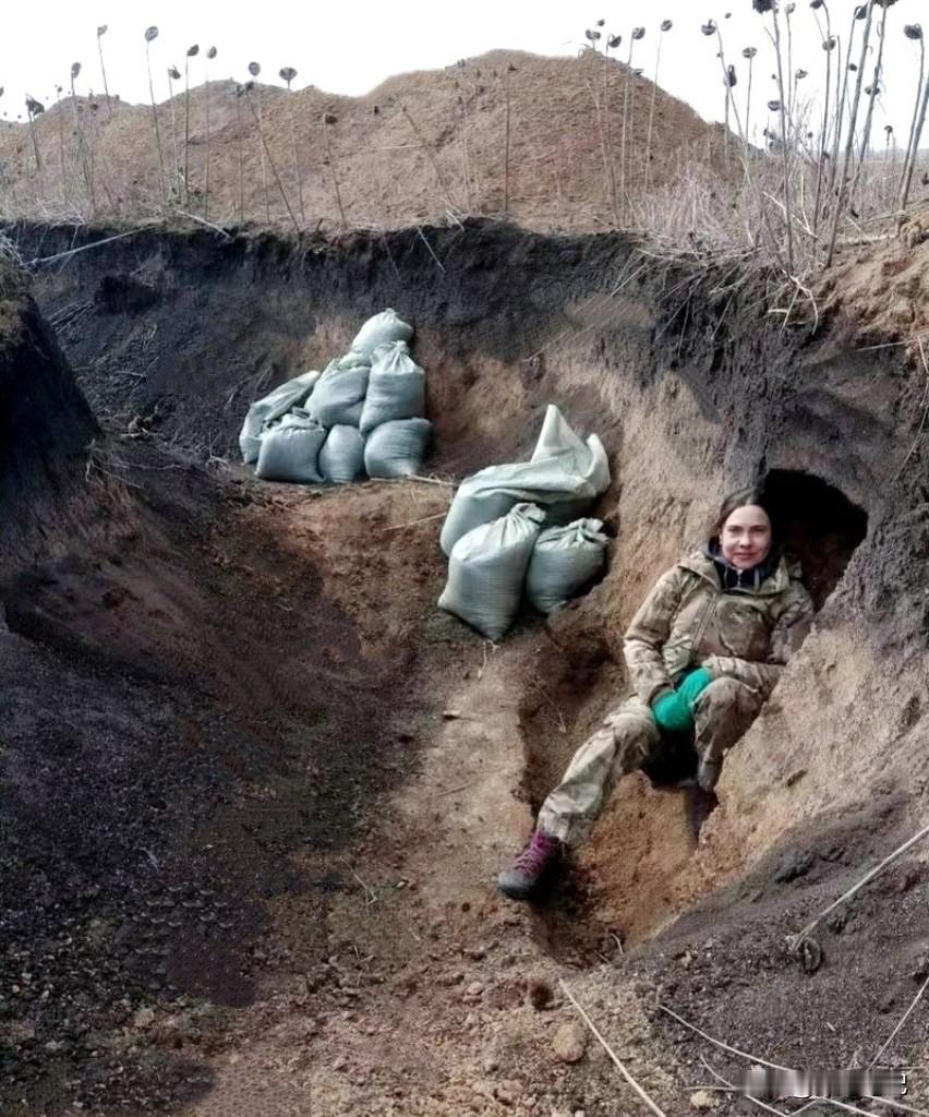 战壕里，这名乌克兰女兵刚放下枪。尘土沾在她脸上，掩体外是持续的爆炸声。她清楚危险