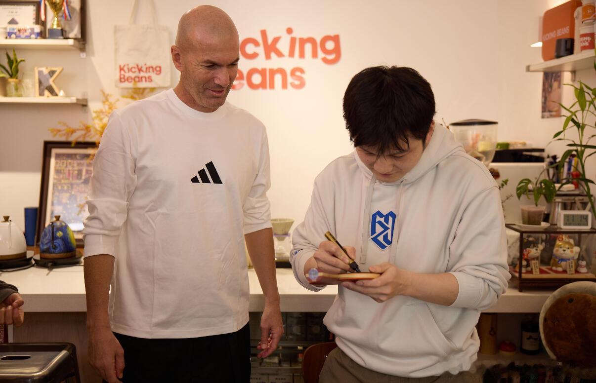 樊振东认真帮齐达内签球拍，齐达内认真帮樊振东签球衣，好朋友加一 