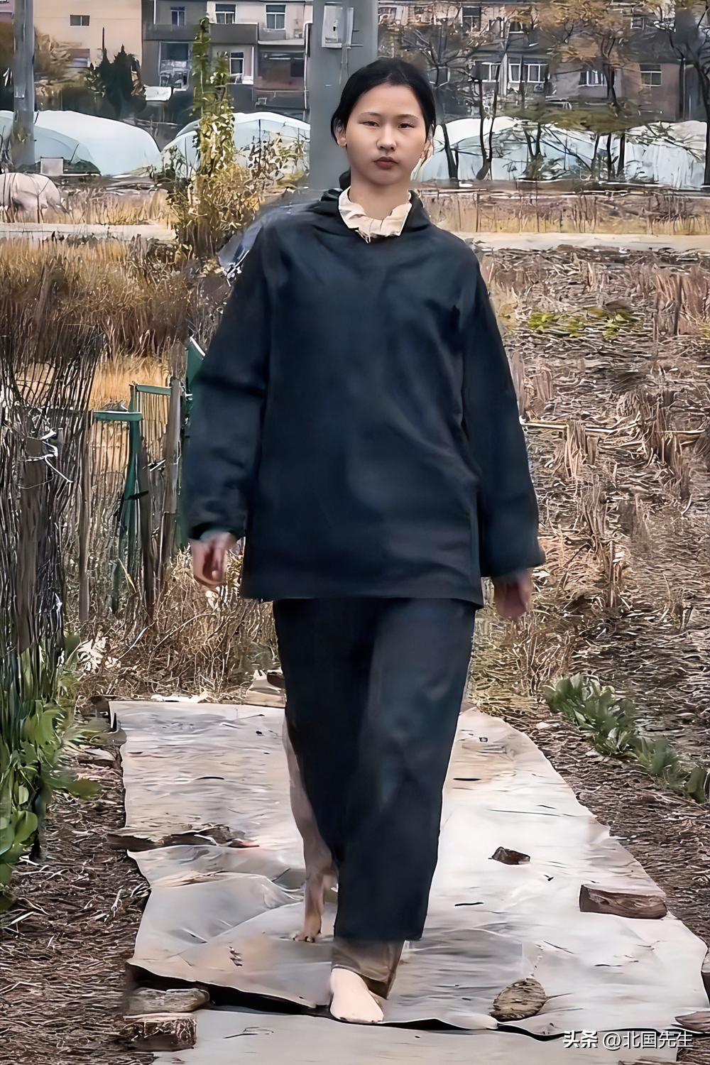 “捡破烂的超模”。

乡村田间的步道，
她穿着朴素的黑色外套和长裤，
身旁跟着一