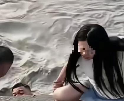 武汉汉口，一女子站在江滩边，丈夫给她拍照，突然丈夫扔下手机，纵身跳入江里。而妻子