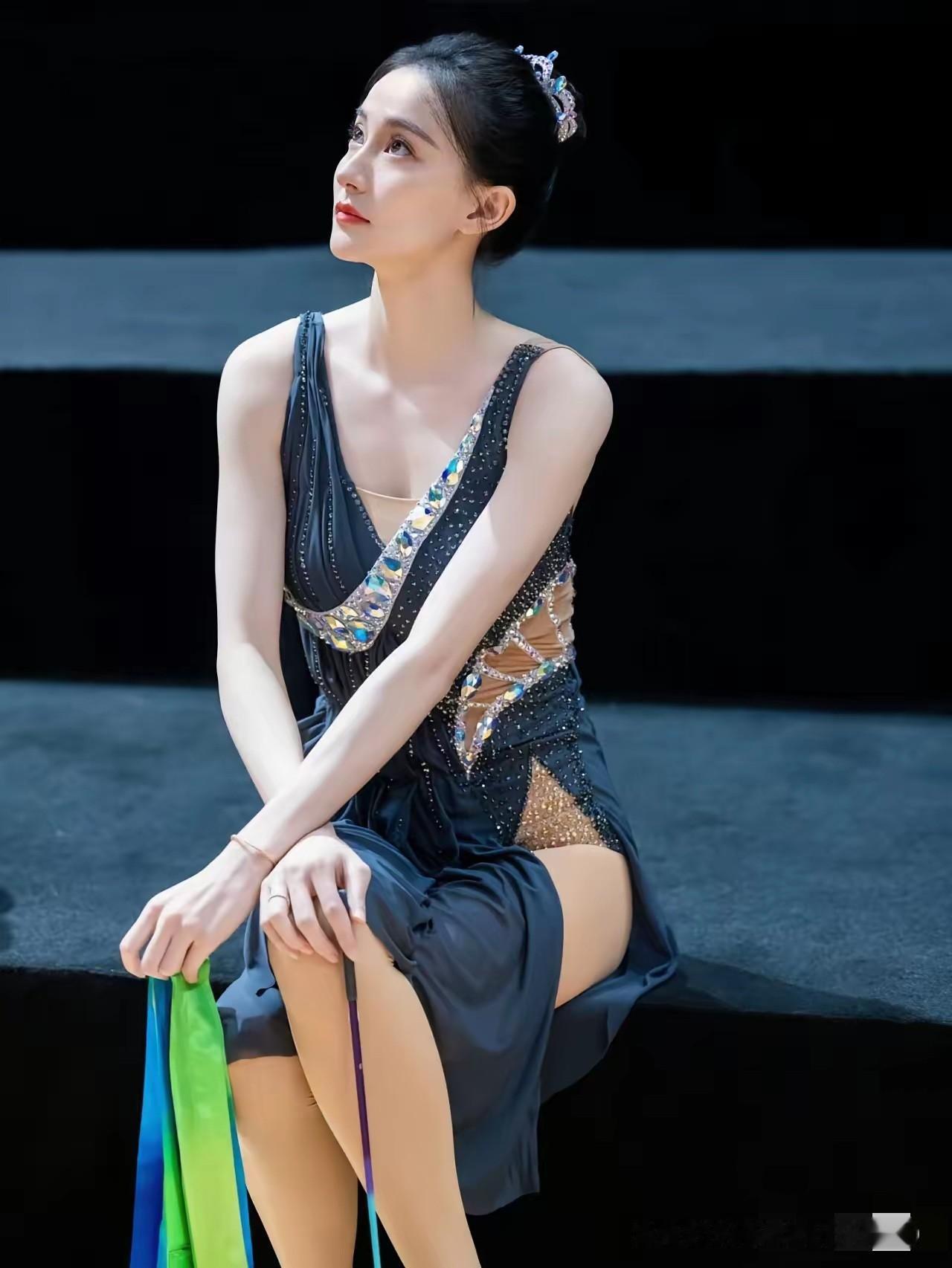 她安静坐着的样子，眼神清澈又温柔，手里握着彩带，仿佛下一秒就要在舞台上翩翩起舞。