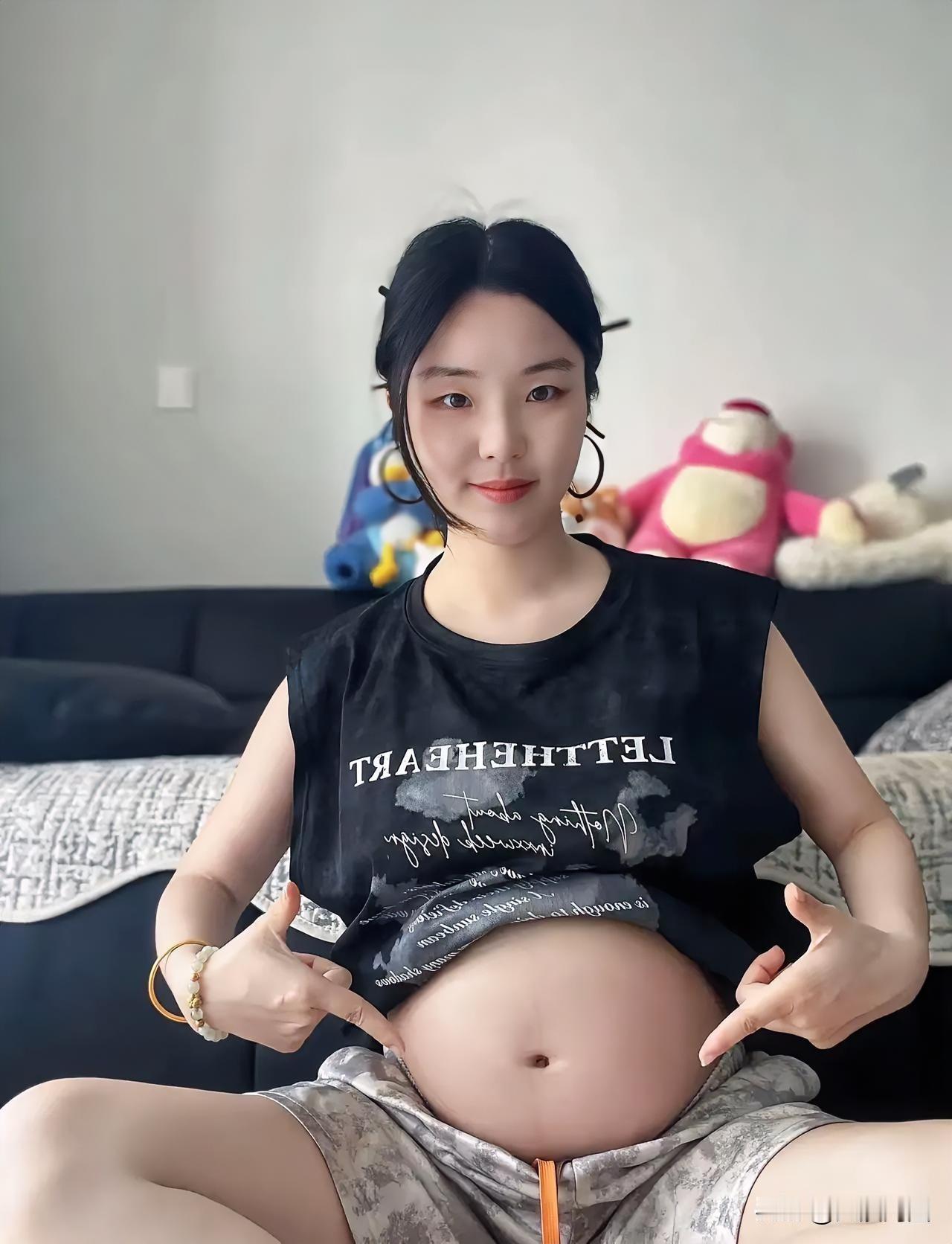 孕妇展示孕肚，微笑拍照。