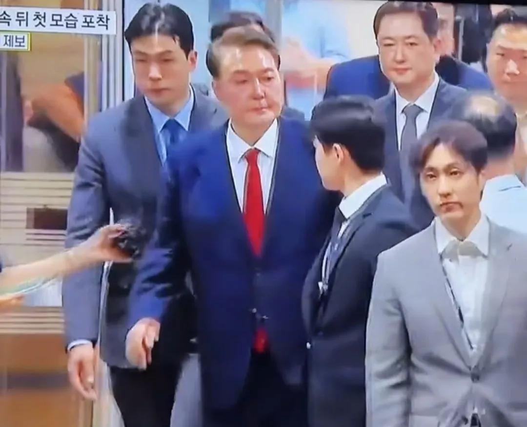 尹锡悦戴着手铐，身穿囚服，脚上戴着电子脚镣，外出就医，去的时候坐的是轮椅。他外出