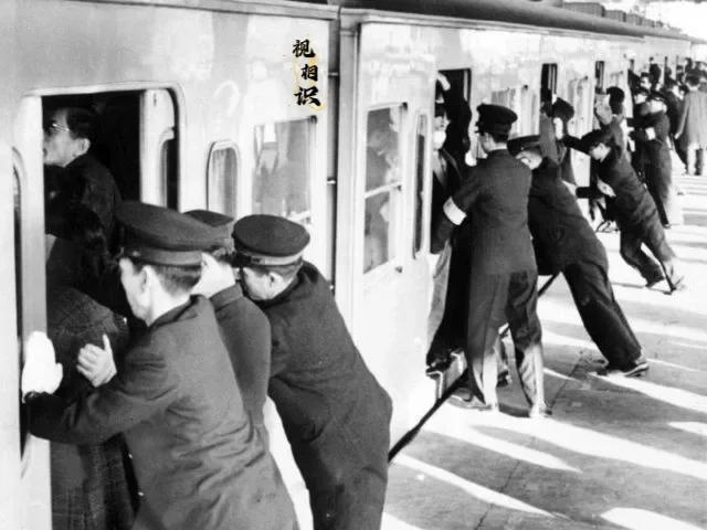 1959年，东京地铁站，站台工作人员正在将人用力推入车厢，每一个门几乎都有二到三...