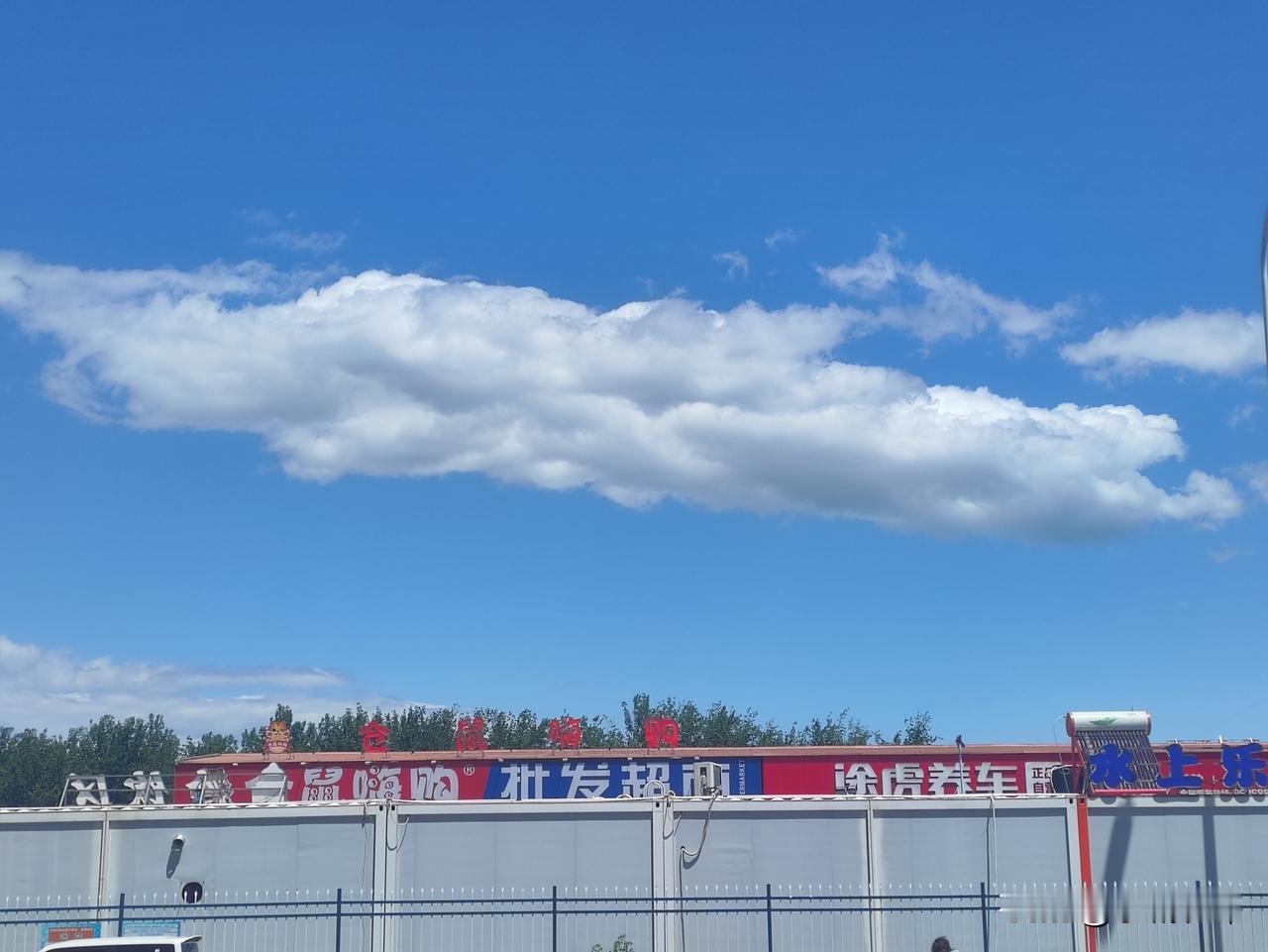 澄澈晴空铺展如洗，大朵大朵的白云慵懒舒展，像蓬松的棉絮随意点缀在透亮的蓝幕之上。
