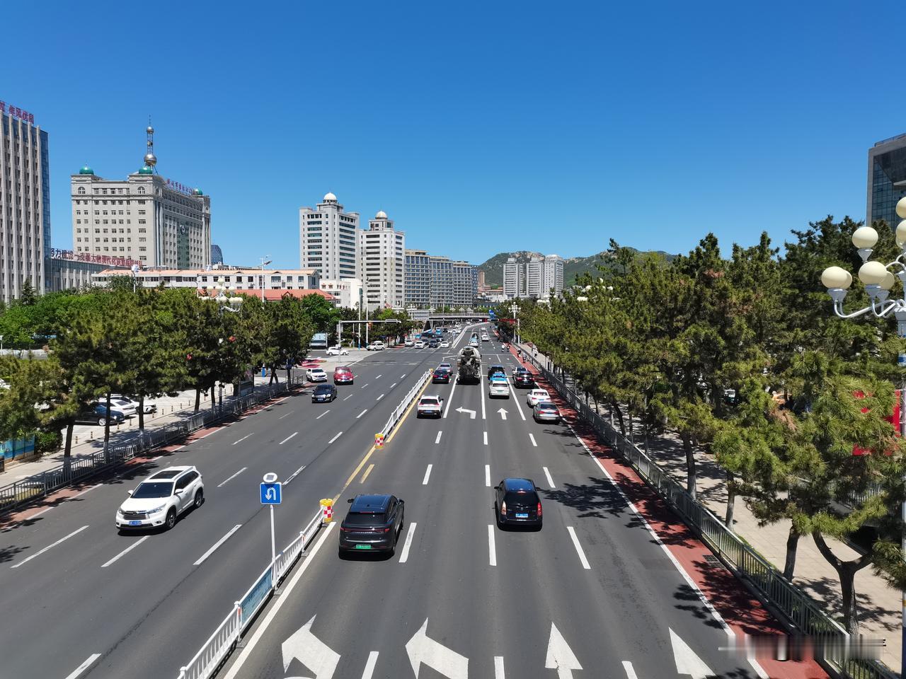 晒图笔记大赛山东威海：晴空铺展在城市上空，宽阔马路车流有序向前，两侧青松整齐列队