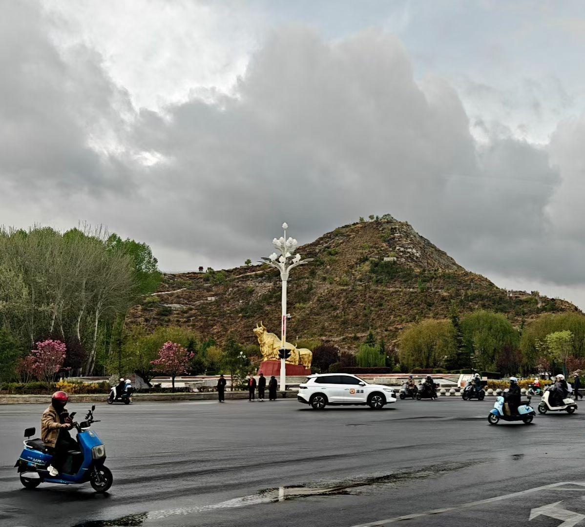 旅行随手拍雨后的拉萨街头，空气里带着湿润的凉意。远处的金牛雕塑在云雾里静静伫立，