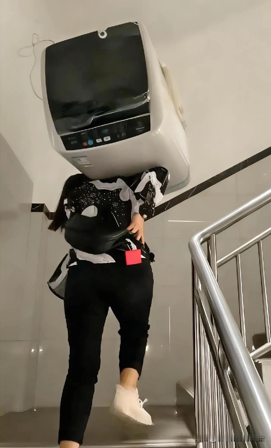 右手叉腰
左手扶着
女子扛着一个洗衣机
一步一个台阶往楼上走。


而且
从1楼