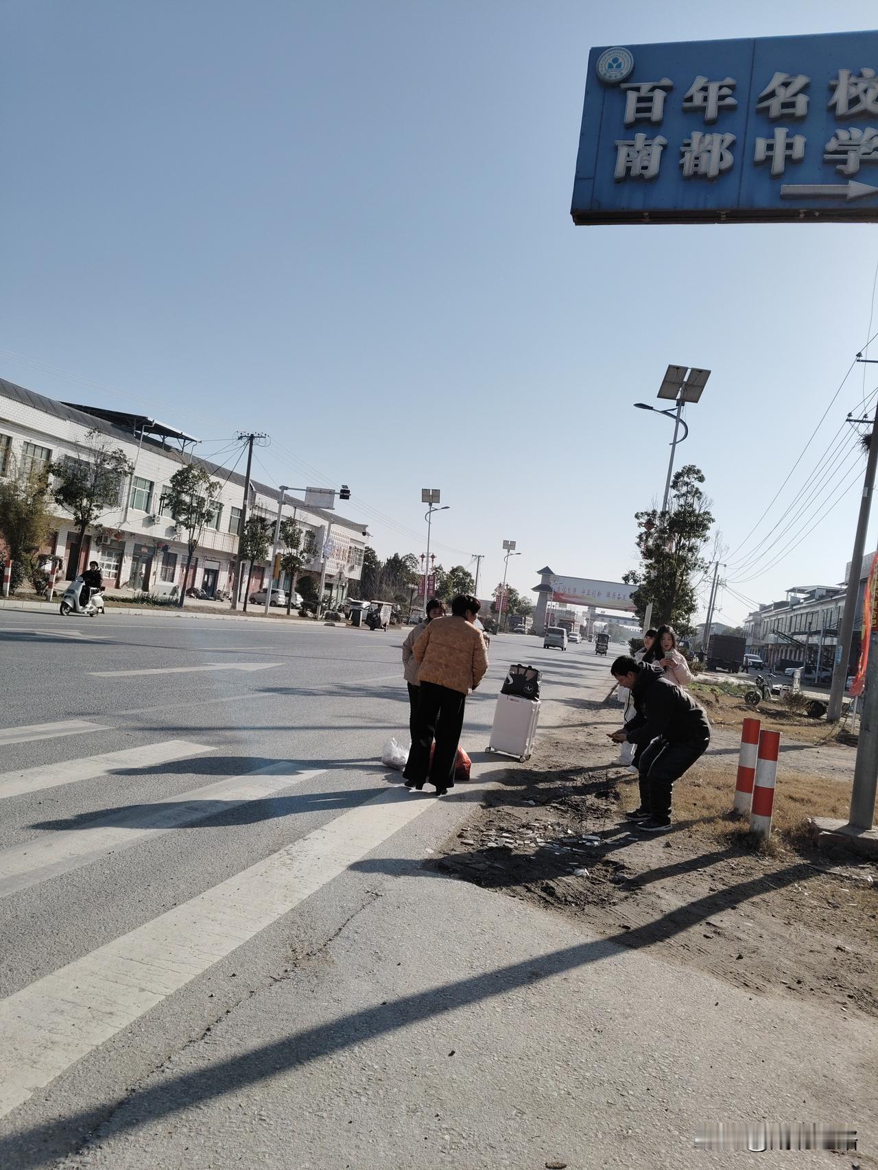 几个人在路边等车，准备去学校。下班路上的景色