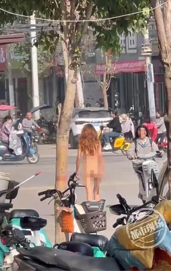 街道上一女子全身赤裸，光脚丫行走，步伐快速，气质身材都很好。
路边行人，也没有一