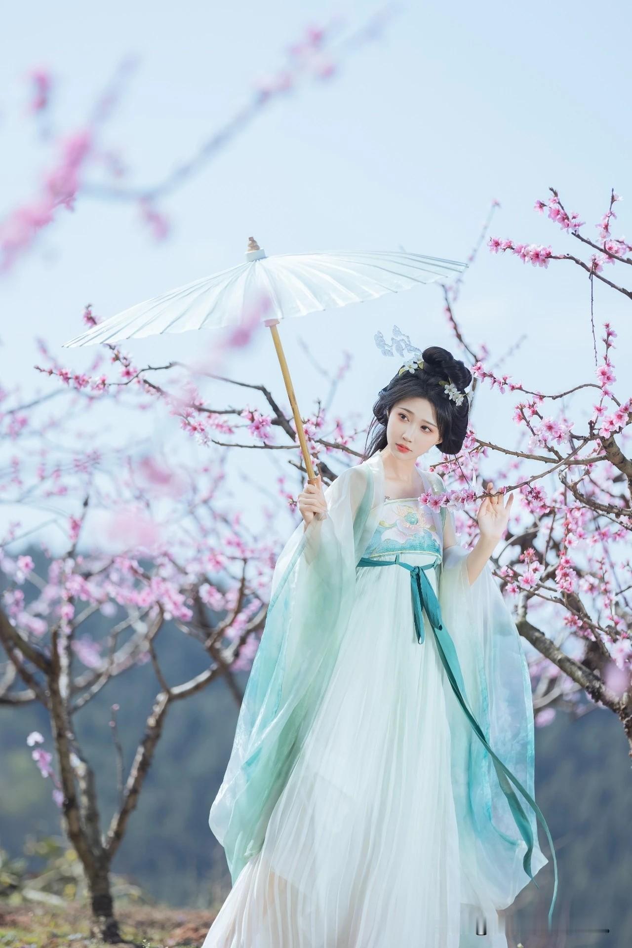像是从山水画里走出的仙子。
身畔是碧波荡漾的江水，
身后是连绵起伏的青山。
不需