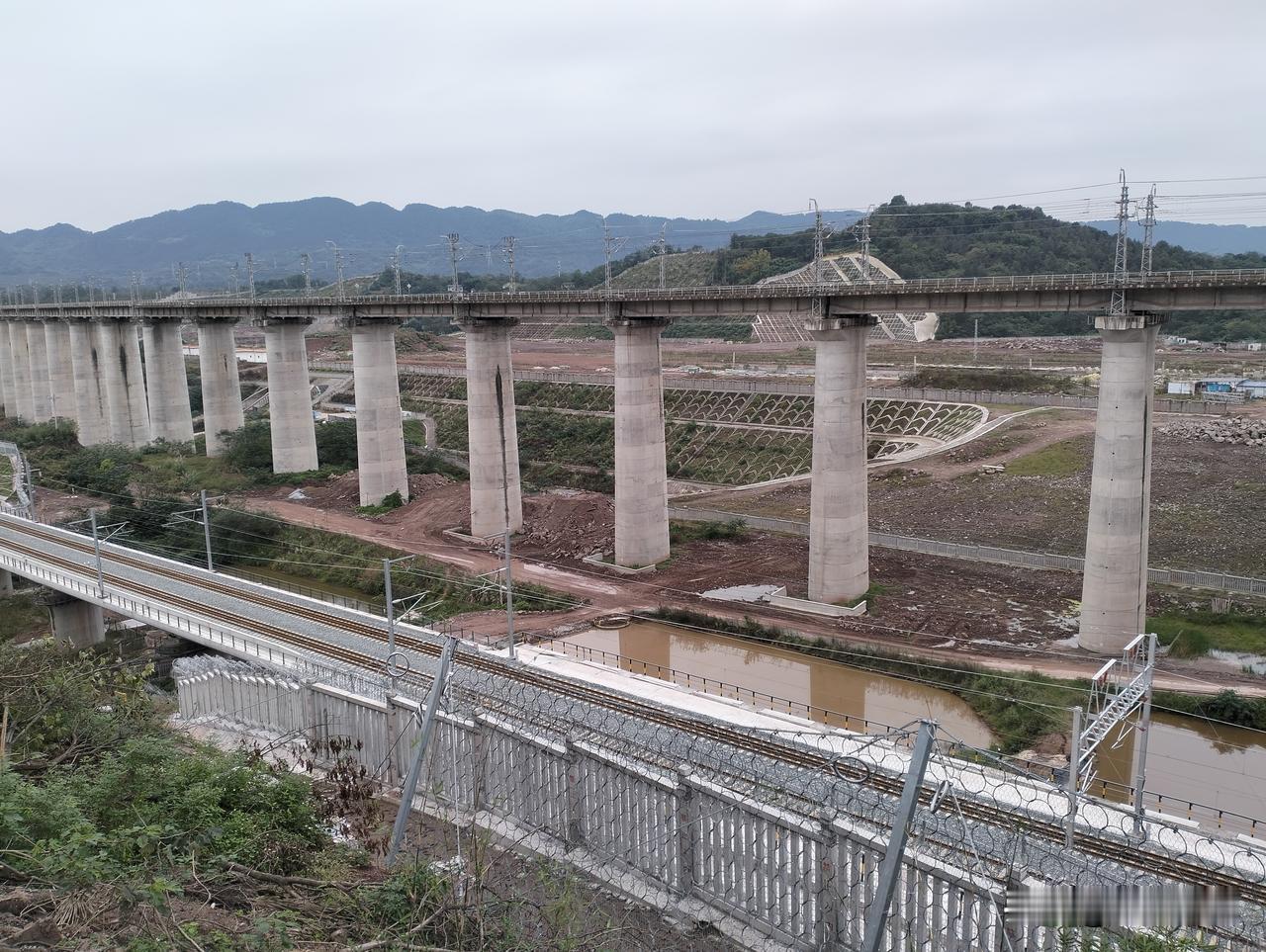 下边是渝万高铁，旁边桥梁是重庆东环铁路，而桥的那边还在建设中的是重庆东客整所，也