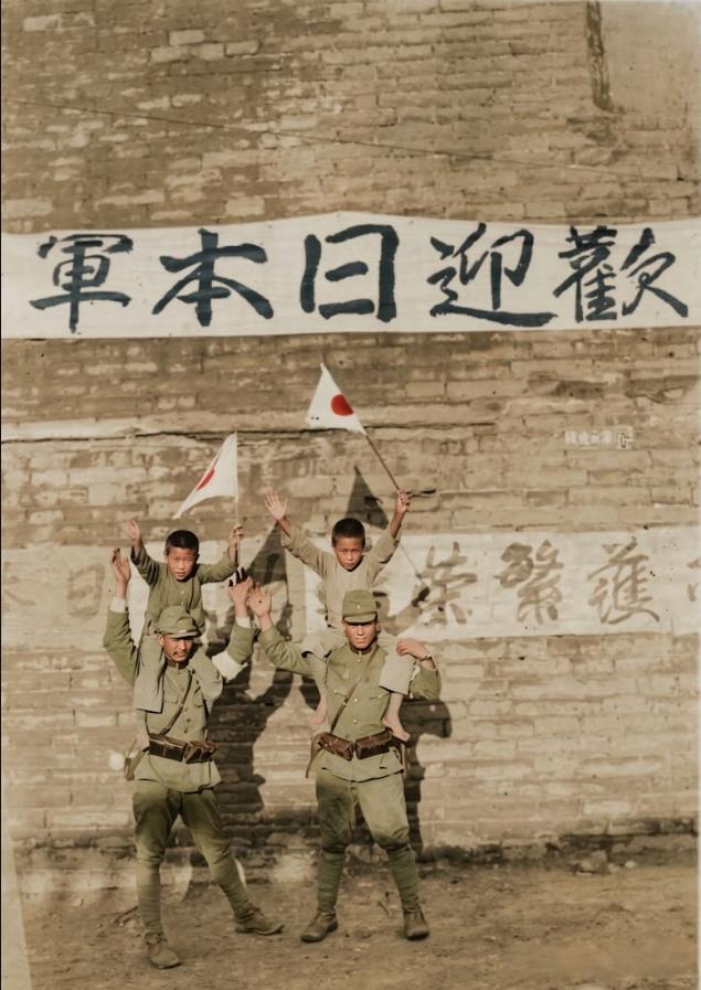 这张照片是抗日战争时期日军典型的“日华亲善”摆拍宣传，砖墙横幅上从右至左写着“欢