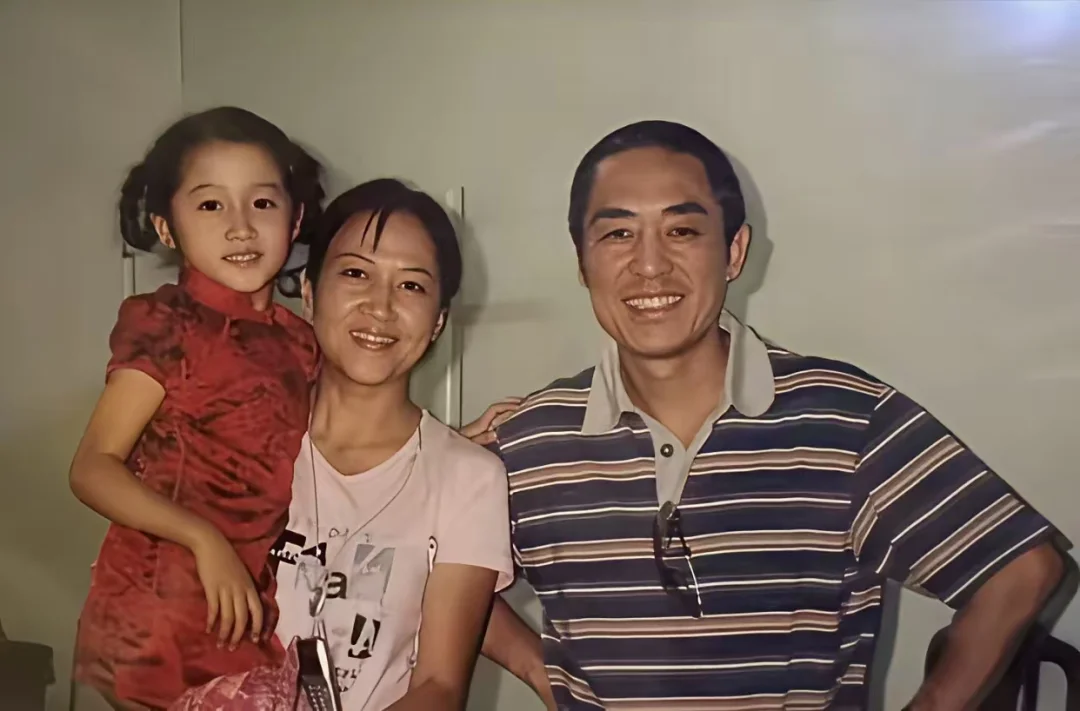 关晓彤被妈妈李君抱在怀里和张艺谋的合照，那时候的关晓彤还很小。扎着两个...