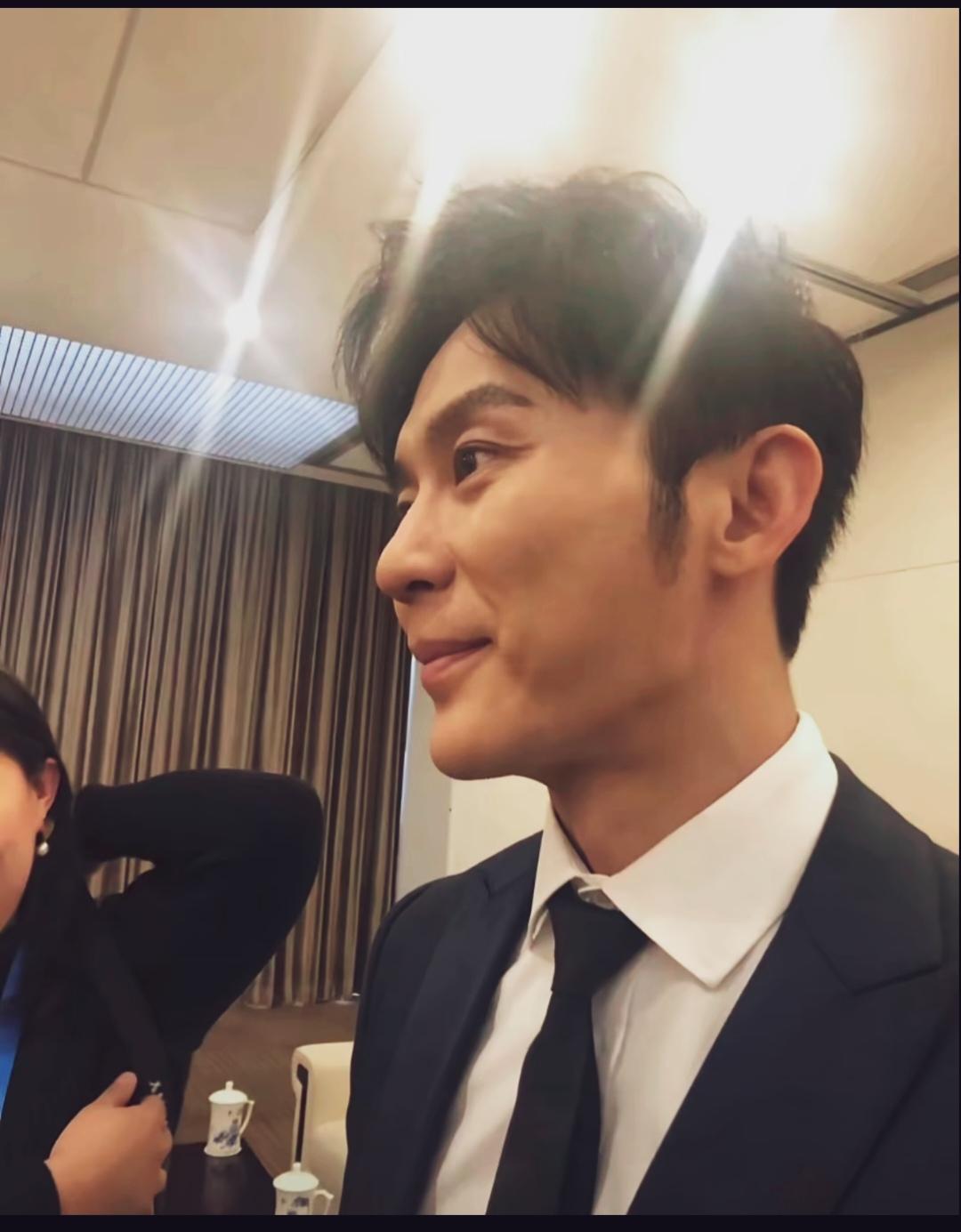 后台抓拍瞬间，镜头中的李晨身着深色西装、白衬衫和领带，状态清爽利落，虽然不年轻了