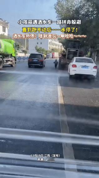 小孩哥在路上偶遇洒水车，撒开脚丫子一路狂奔躲避水雾，那小短腿倒腾得飞快，仿佛身后