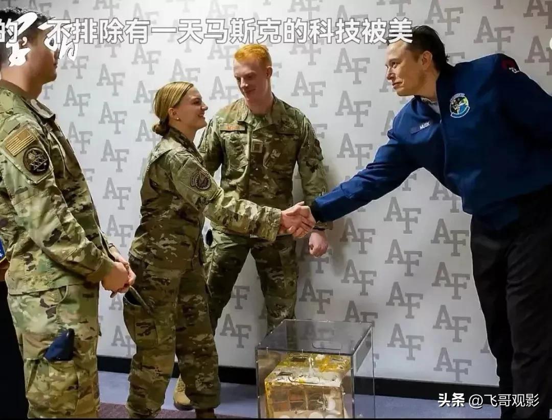 马斯克见士兵，他与女兵握手，与男兵合影。那女兵有点矮小，她看着马克斯笑眯眯，马克