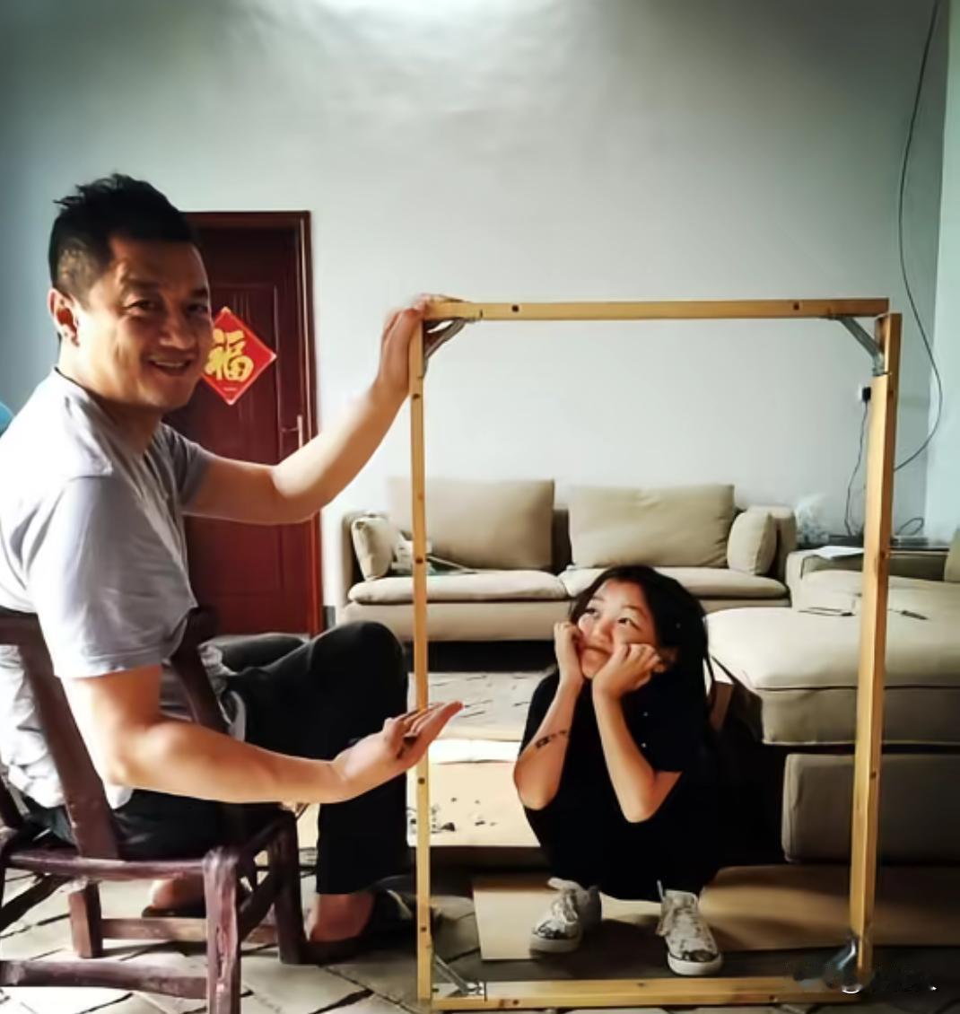 2015年，李亚鹏扶着木画框。李嫣蹲在框内双手托脸，玩框中拍照小游戏，氛围轻松温