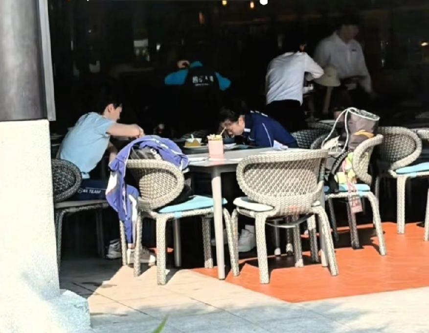 WTT新加坡大满贯时，被偶遇在餐厅吃饭的王曼昱和徐奕。两个人对着坐在餐桌前吃饭。