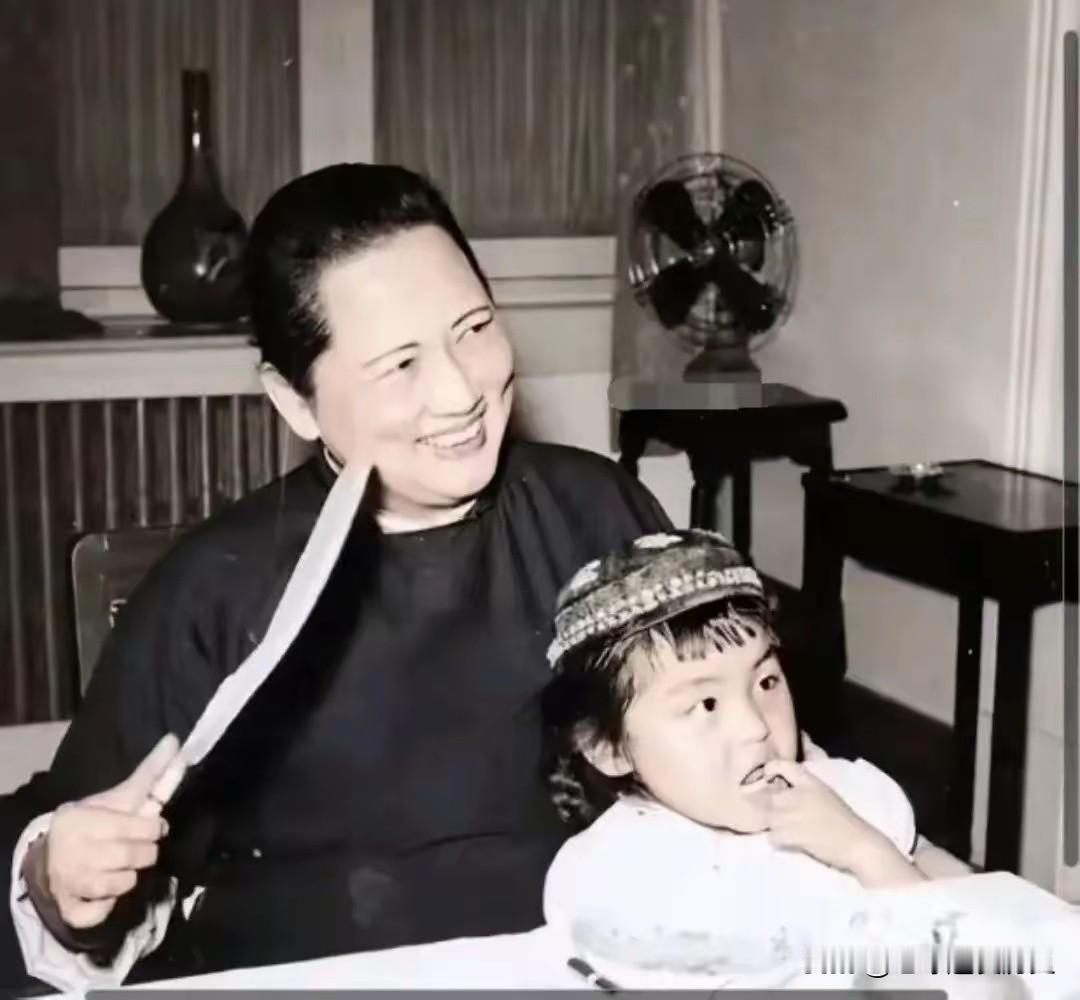 这张黑白照片定格了宋庆龄先生与养女隋永清的温情瞬间。
宋庆龄手持折扇，笑意温柔，