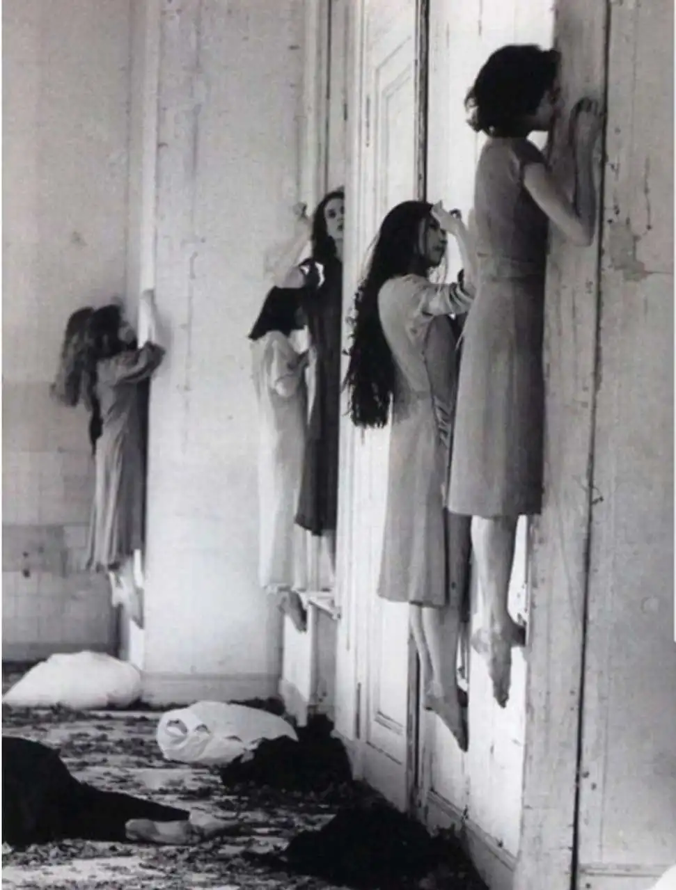 1977年，德国芭蕾舞演员们正在伸展小腿肌肉，踩在为此设计在墙洞上。 ...
