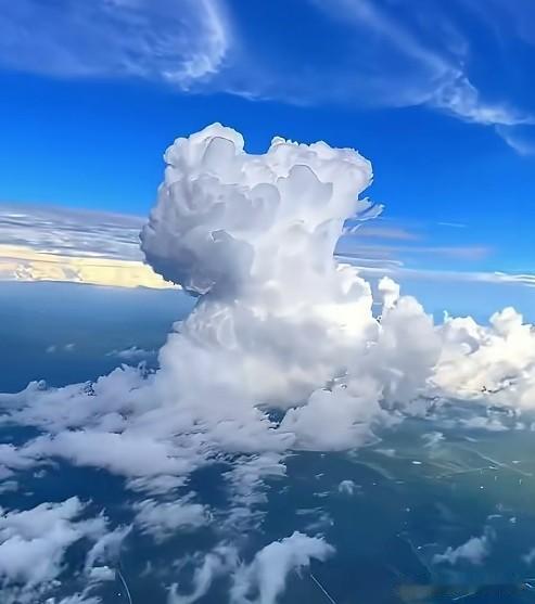 乘机穿行于高空之上，澄澈蓝天铺展天际，一簇簇积云拔地而起，层层叠叠铺成壮阔云海。