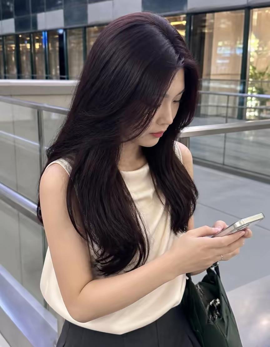 一个长发女生在户外看手机。