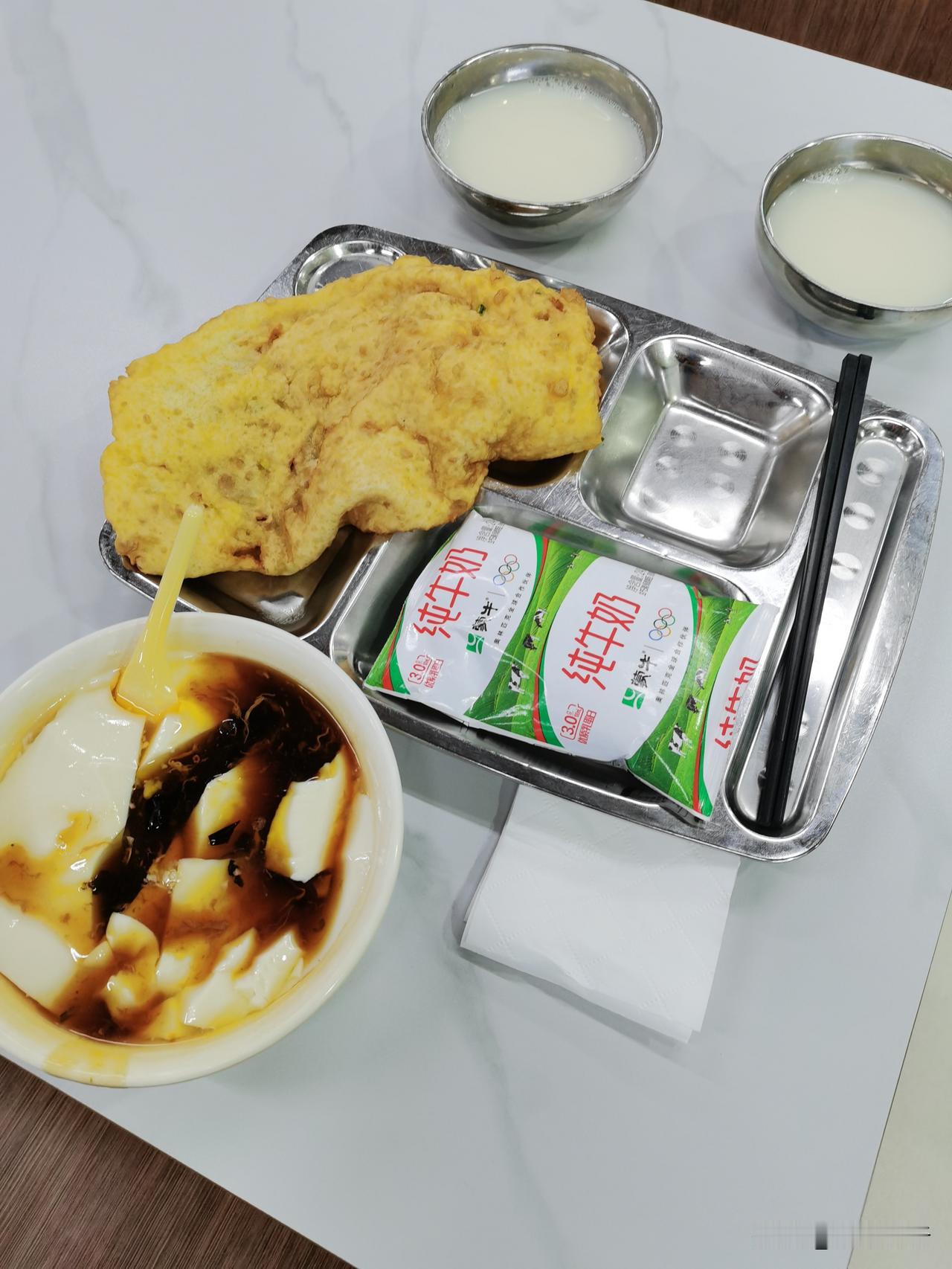 在单位食堂吃早饭，来份炸饼和豆腐脑。
炸饼外酥里嫩，豆腐脑咸香滑嫩。
我把炸饼撕