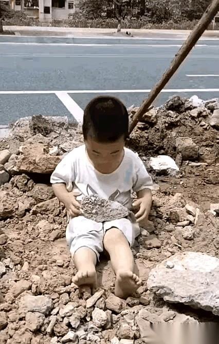 网上刷到一个小男孩的视频，也就两三岁的样子。
他一个人坐在马路边的石堆里，吭哧吭