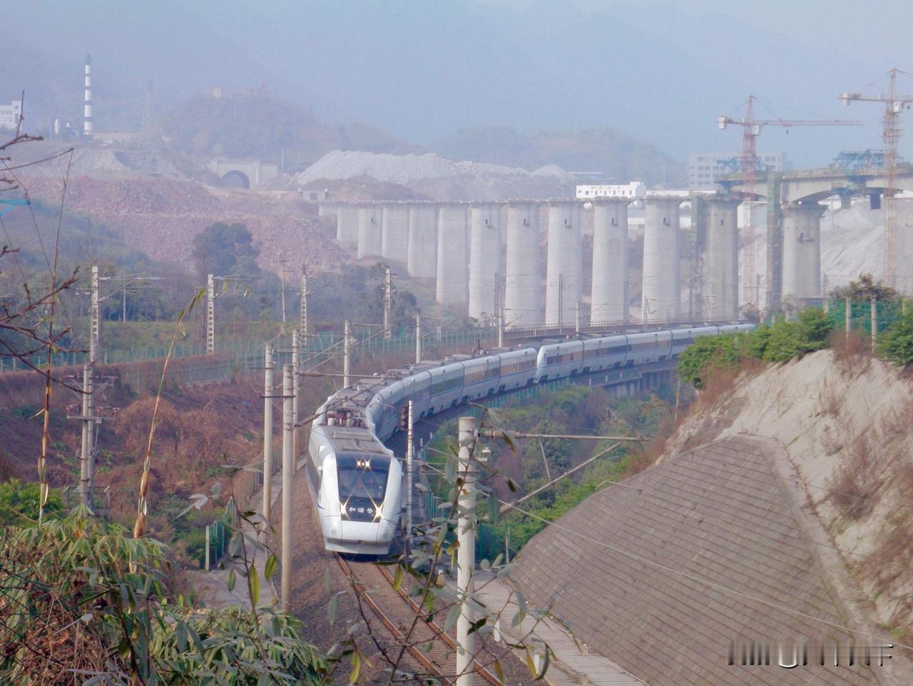 2013年2月，遂渝铁路上运行的重联动车组，远处建设中的桥梁是兰渝铁路黄桷树大桥