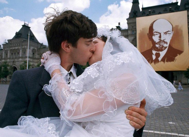 1990年，一对新婚夫妇在莫斯科红场列宁画像前接吻。 