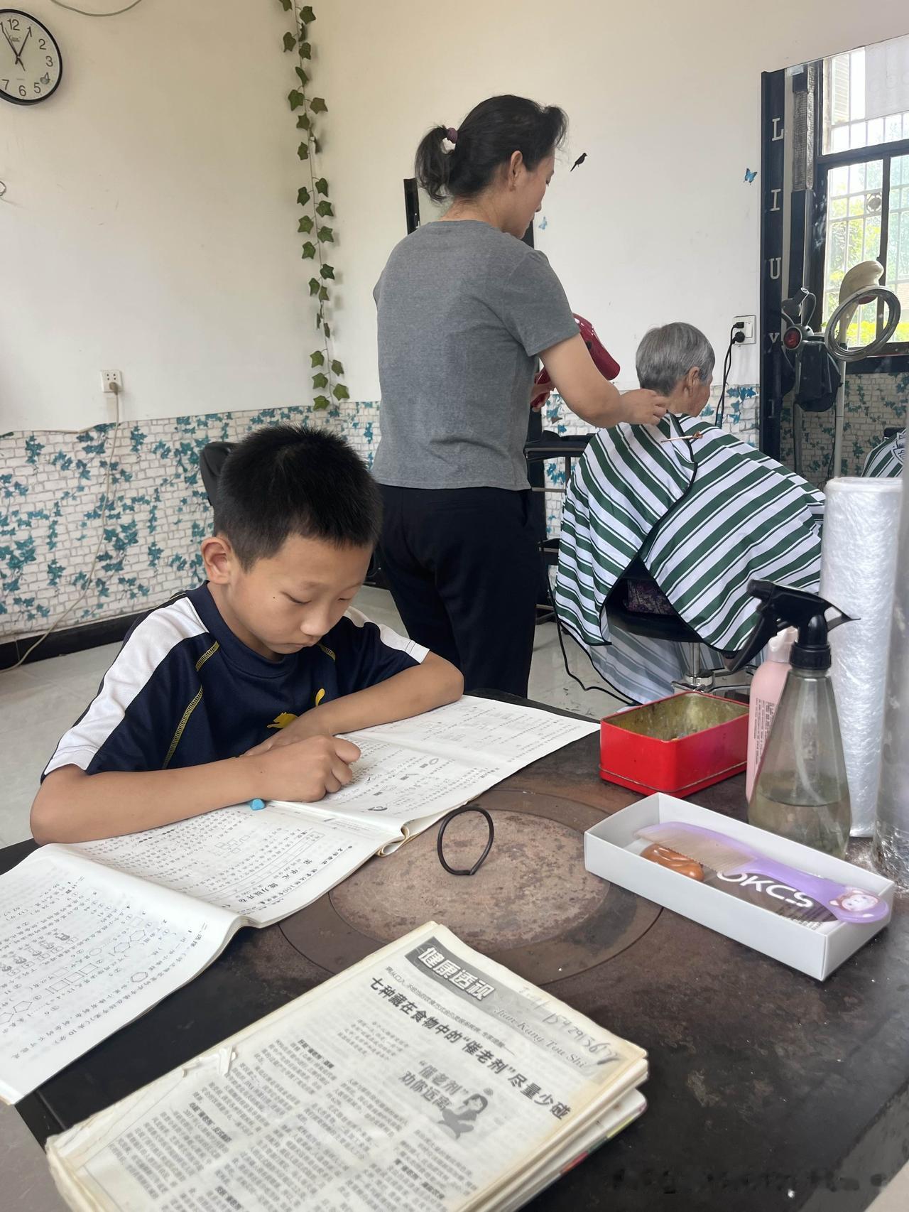 妈妈正在工作，儿子就在一旁学习。他的学习桌，是尚未拆掉的取暖炉。瞧他那认真学习的