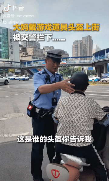 5月4日，安徽淮南街头，一位大妈戴着小孙子的玩具头盔骑电动车，被交警拦下询问“这