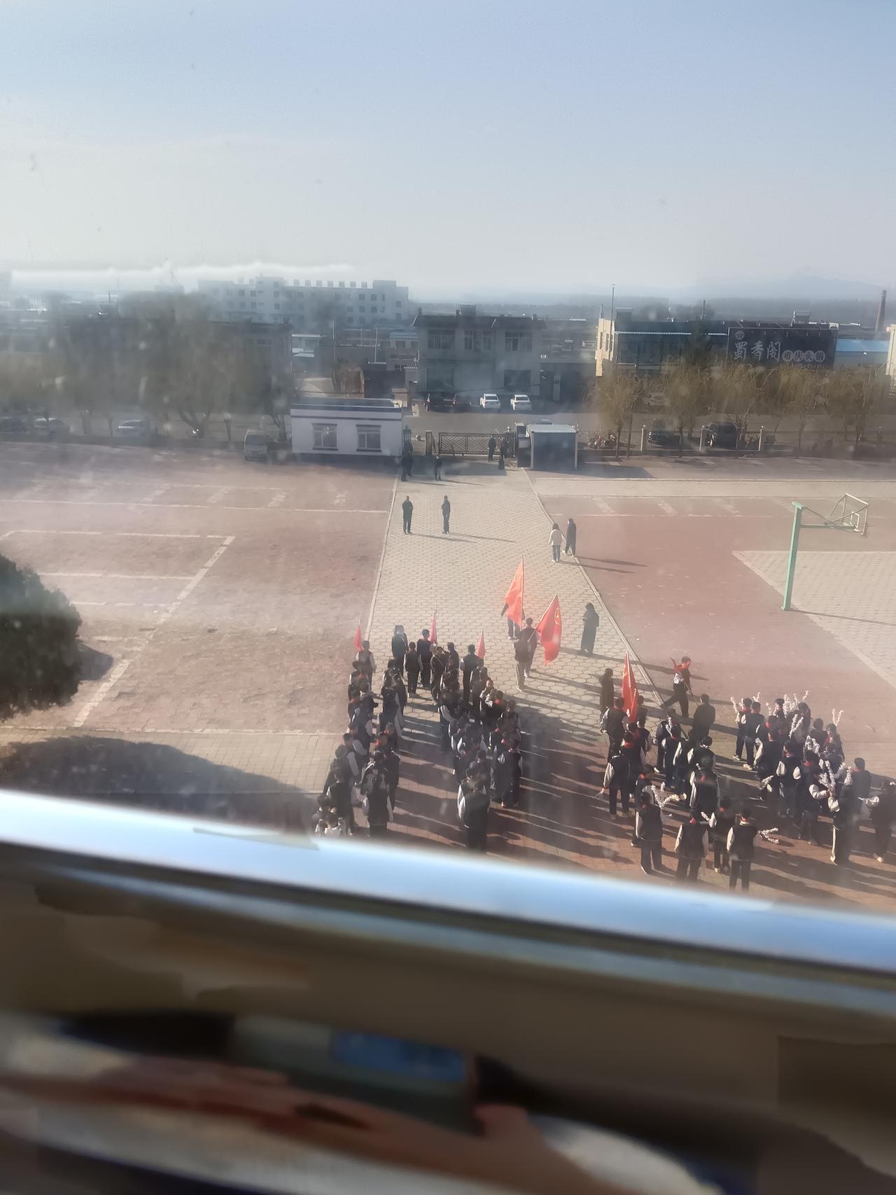 红旗招展，一群学生在操场上排成队伍，准备参加祭扫烈士墓的活动。烈士公园扫墓 后人