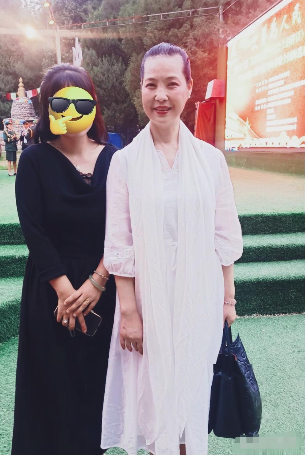 这张照片里的梦鸽穿着简约素雅的长款白衣，气质温婉平和，笑容亲切，面色红润，整个人