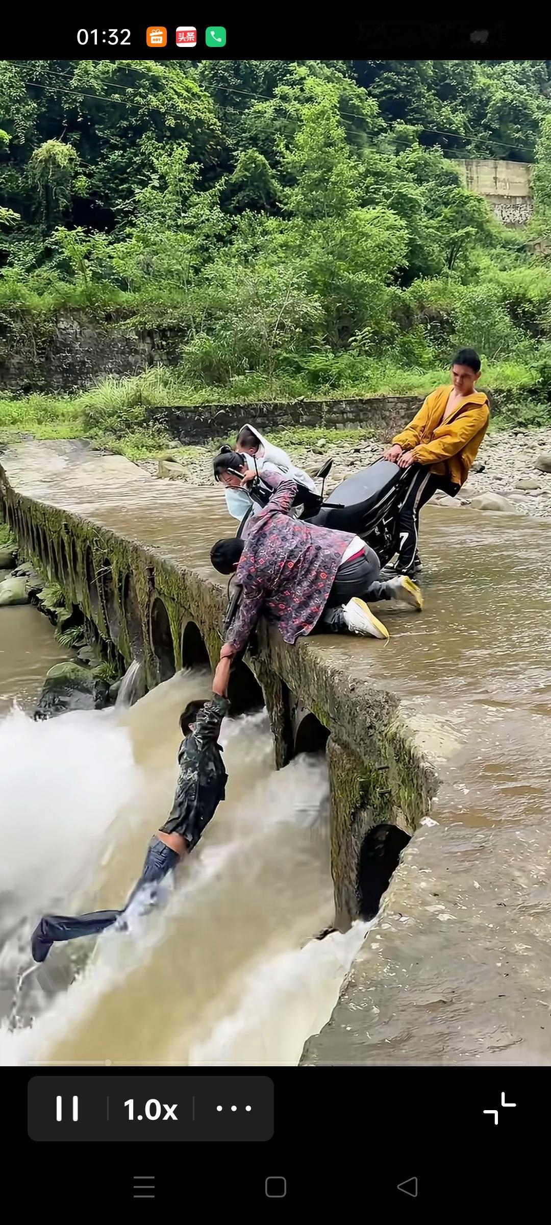 两个男同志骑摩托车不慎，摩托车的前半部分已经跌入桥下，其中一个人随着摩托车跌下时
