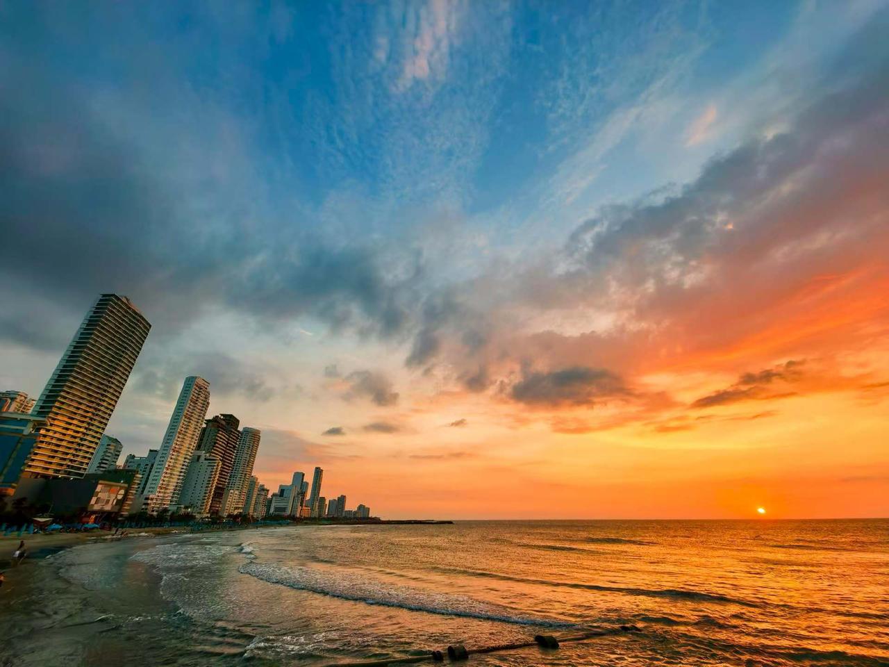 天空被橙红色晚霞染透，云层层次分明；海面波光粼粼，反射着夕阳余晖。