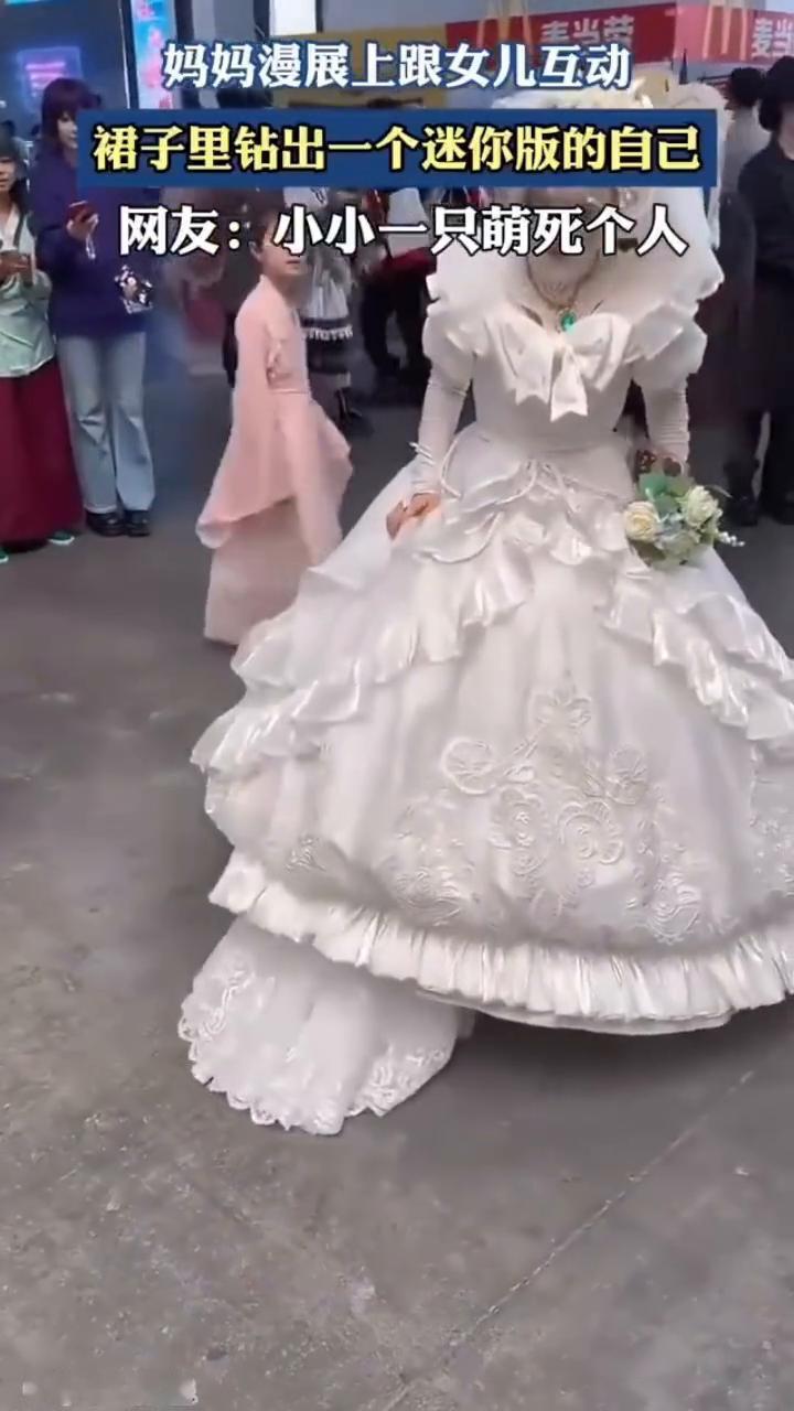 妈妈漫展上跟女儿互动，裙子里钻出一个迷你版的自己。
网友：小小一只萌死个人。
来