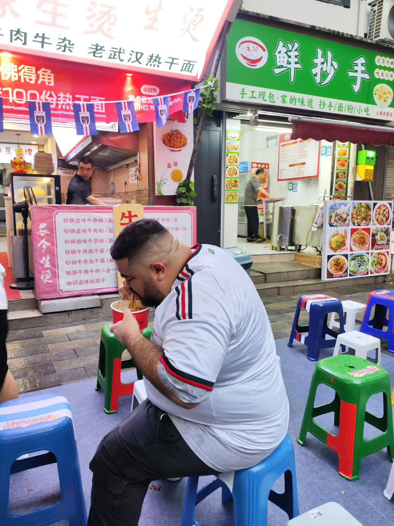 俩老外武汉过早看球赛用中文争两位外国朋友在武汉街边惬意过早，一边嗦着本地早点，盯